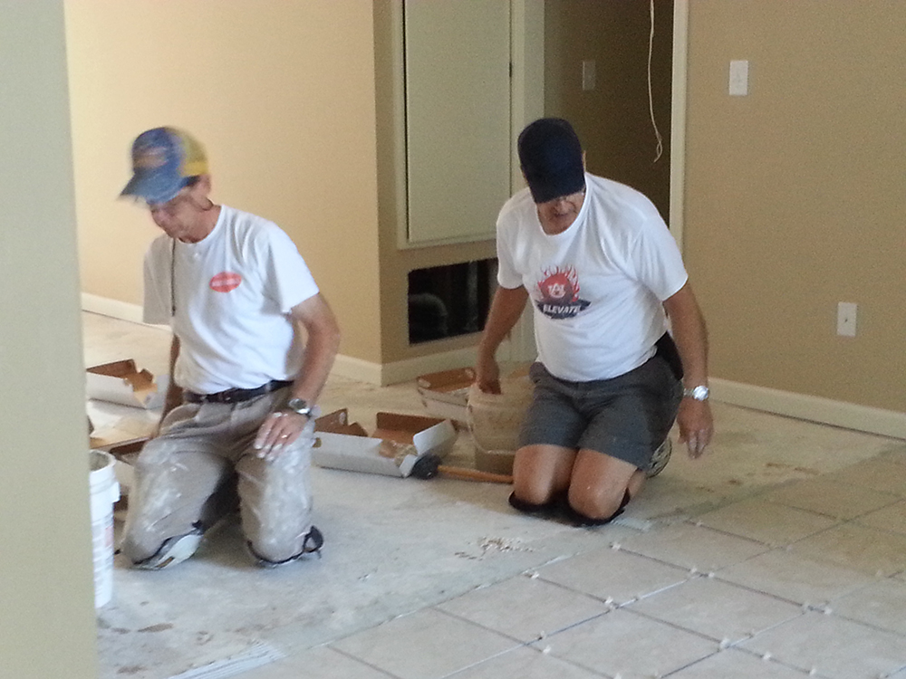 Rusty Taylor & Buzz Farerro on knees laying tile maybe a prayer now and then